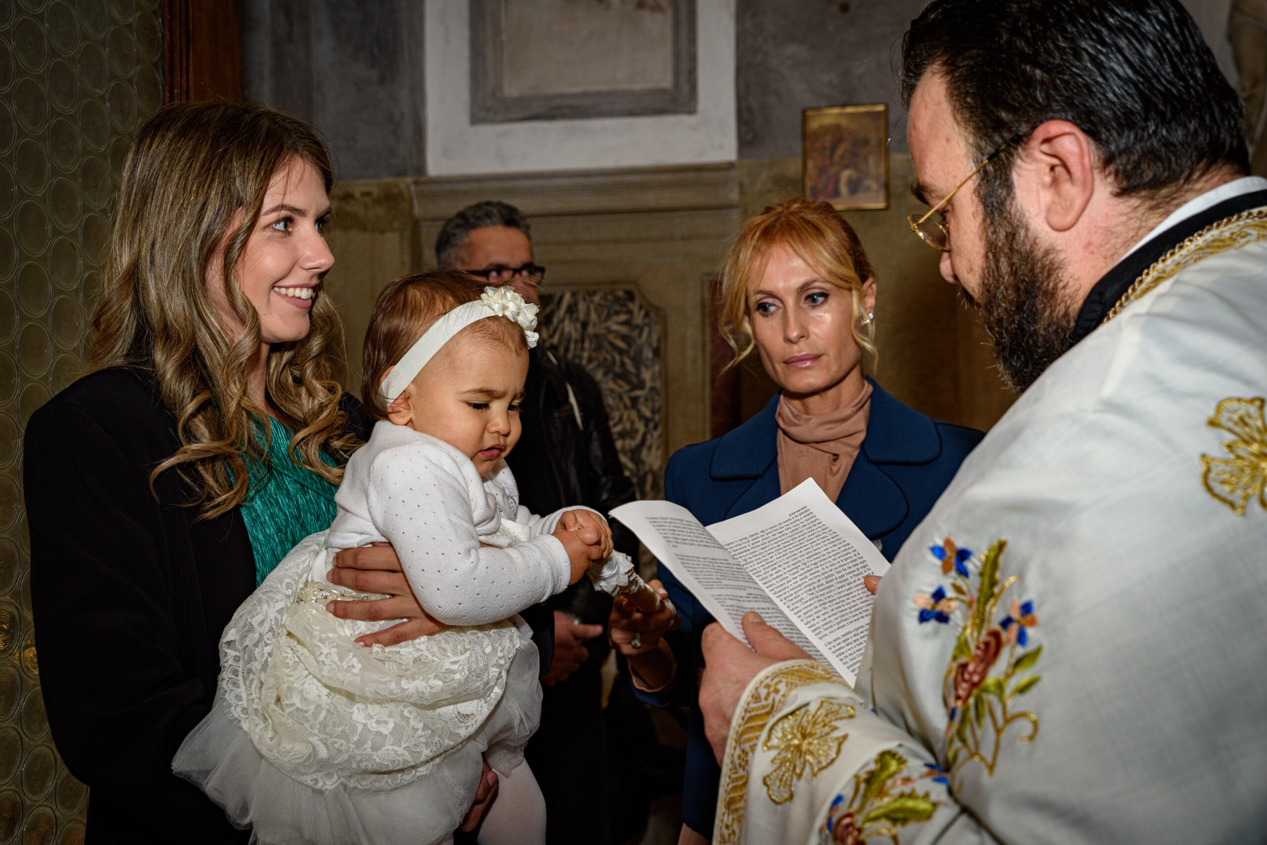 Parenti con una bambina durante la cerimonia del battesimo ortodosso , progetto Storie da condividere a Padova