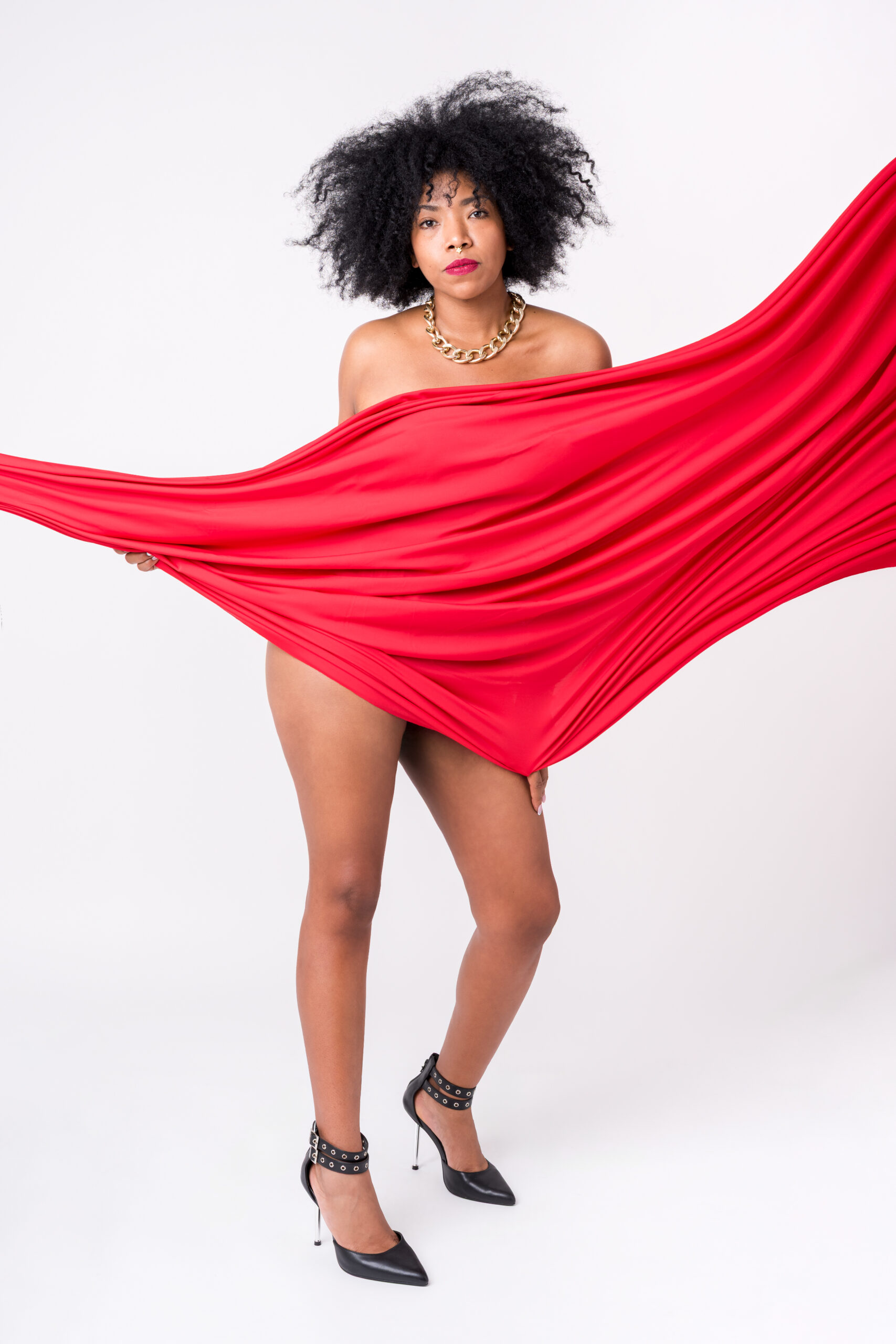 Ritratto boudoir in studio con grande tessuto rosso, collana dorata e scarpe con tacco, servizio boudoir a Padova