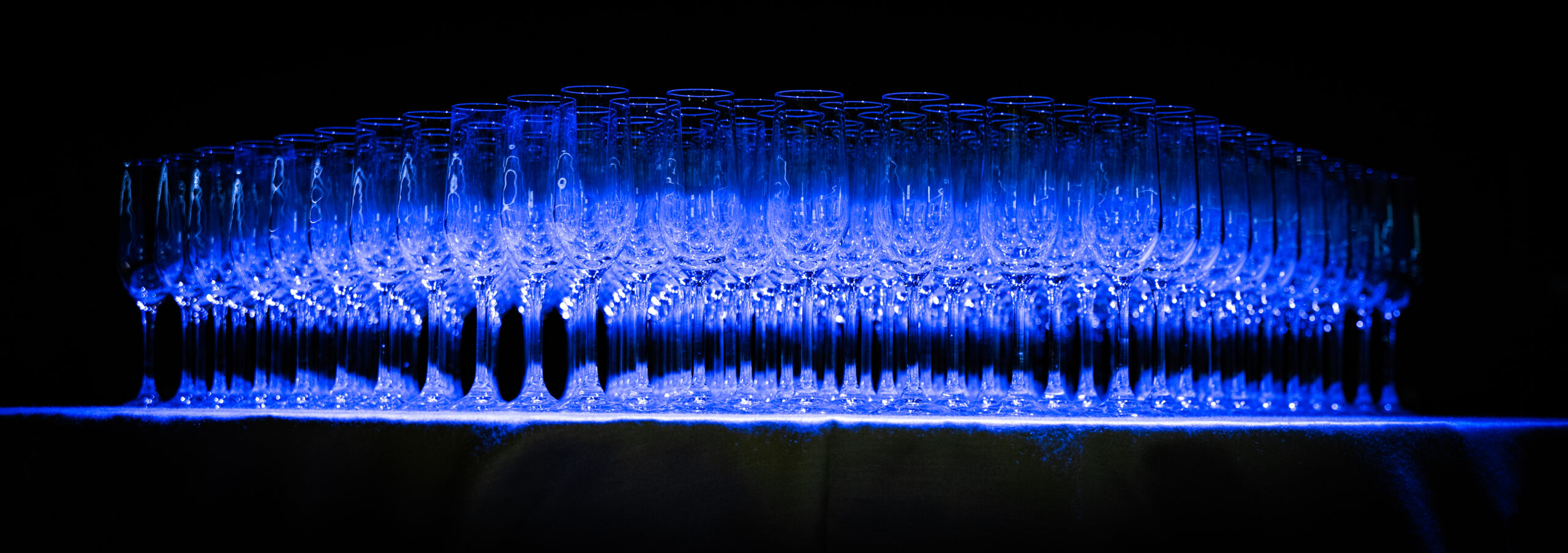 Calici disposti per il brindisi durante un evento aziendale illuminato di blu, servizio fotografico business events a Padova