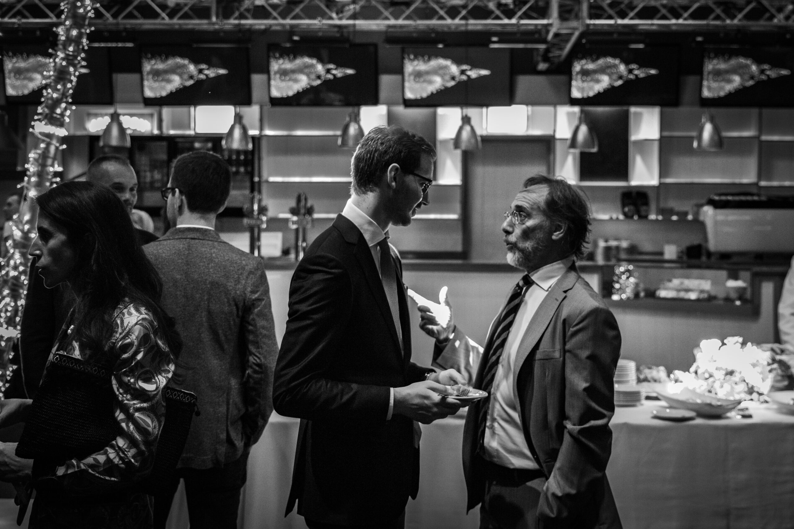 Partecipanti conversano accanto al buffet durante un evento aziendale in bianco e nero, servizio fotografico business events a Padova