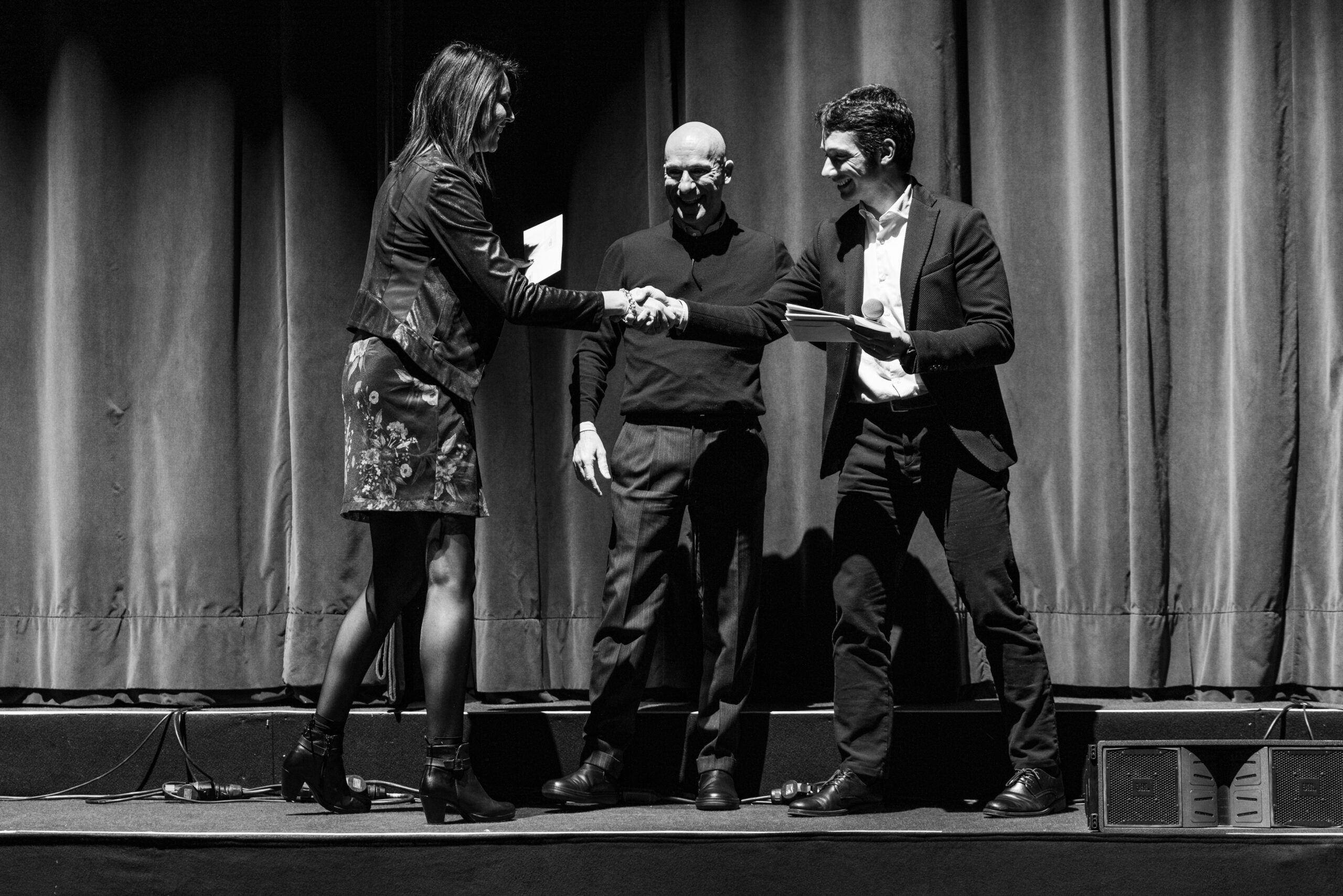 Stretta di mano durante una premiazione sul palco in bianco e nero, servizio fotografico business events a Padova