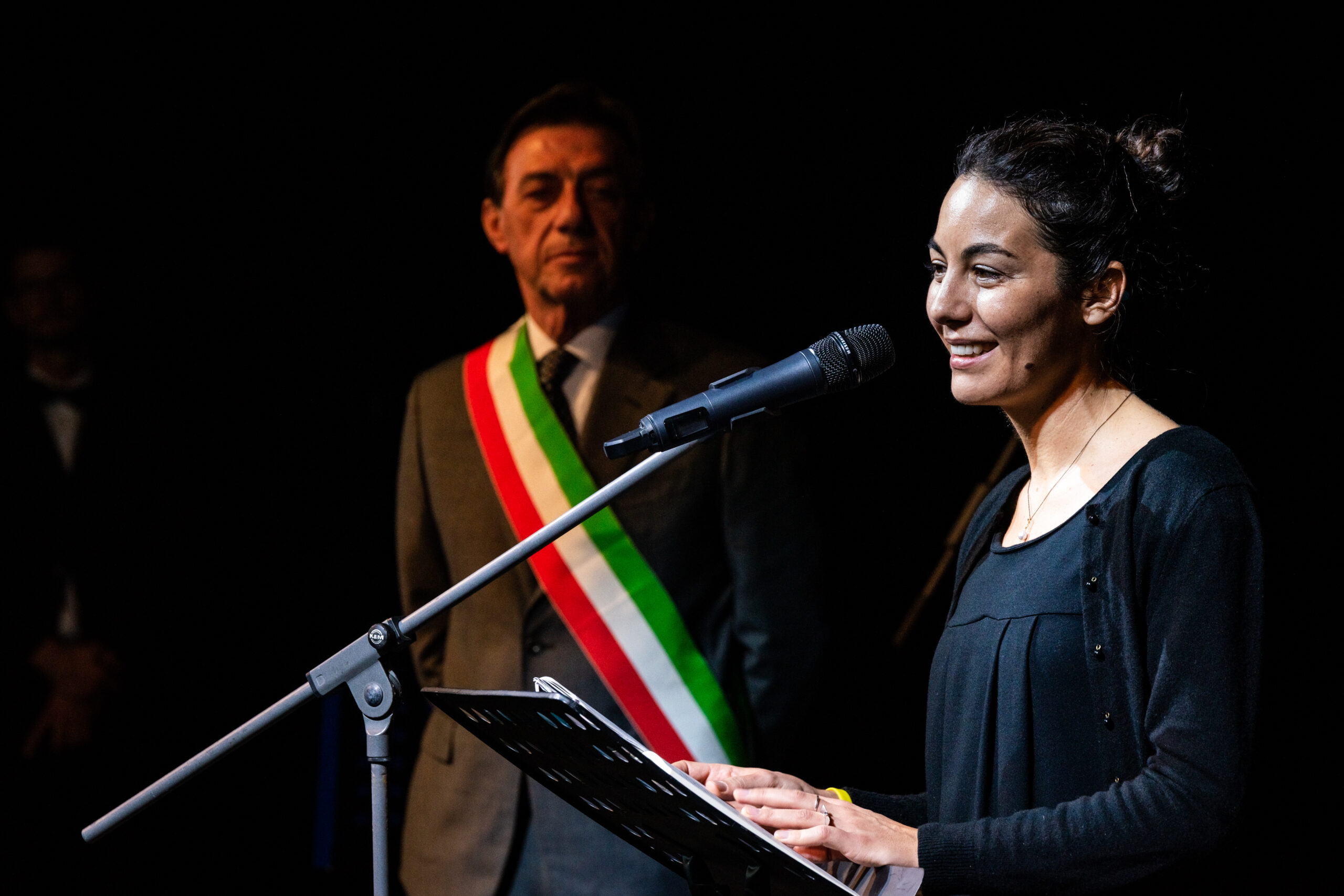Relatrice al microfono con il sindaco di Padova Sergio Giordani sullo sfondo durante un evento pubblico