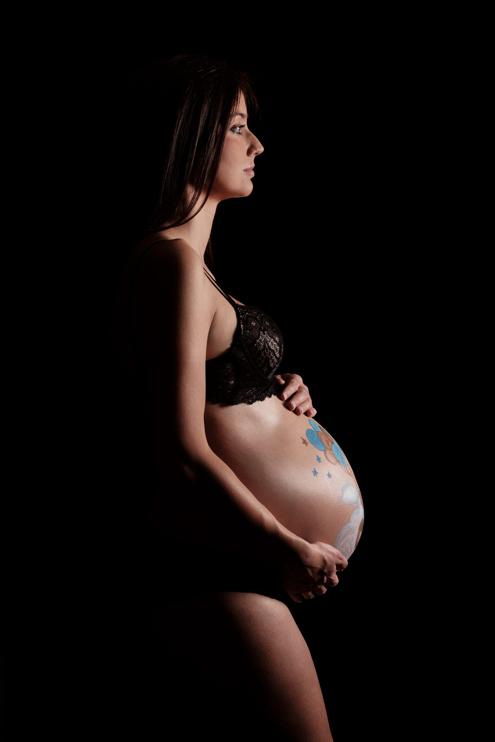 Ritratto di futura mamma di profilo con pancione dipinto, progetto Storie che iniziano a Padova
