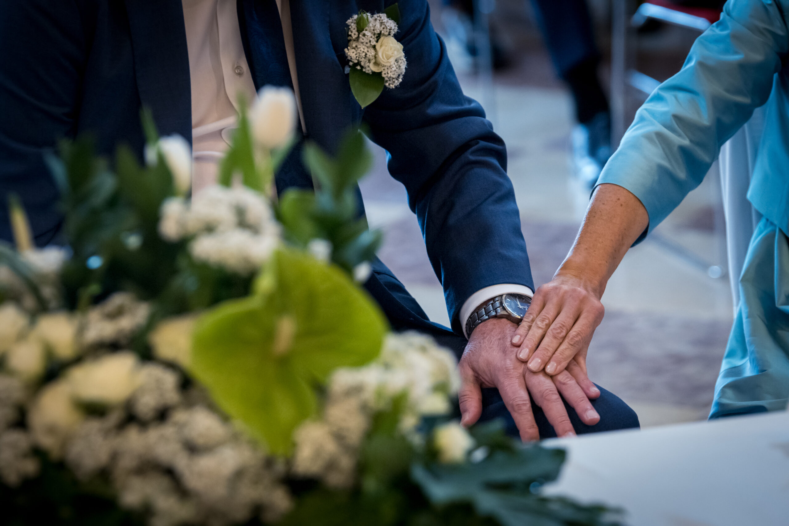 Mani degli sposi unite accanto ai fiori della cerimonia, progetto Storie da condividere a Padova