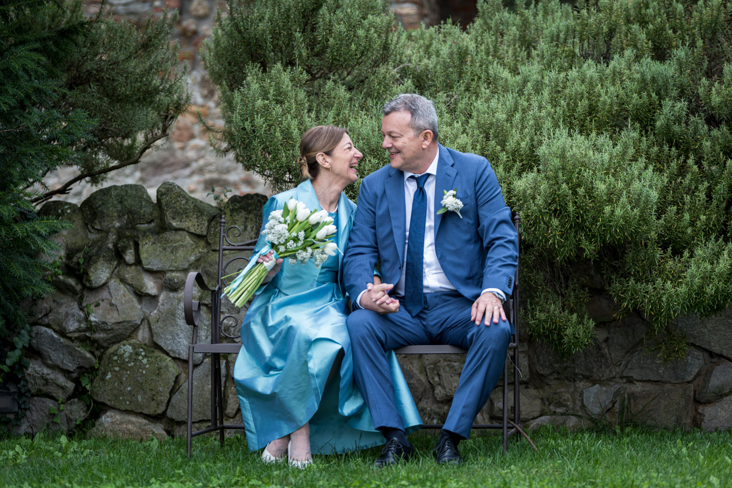 Sposi sorridono seduti su una panchina in giardino nel giorno del matrimonio, progetto Storie da condividere a Padova