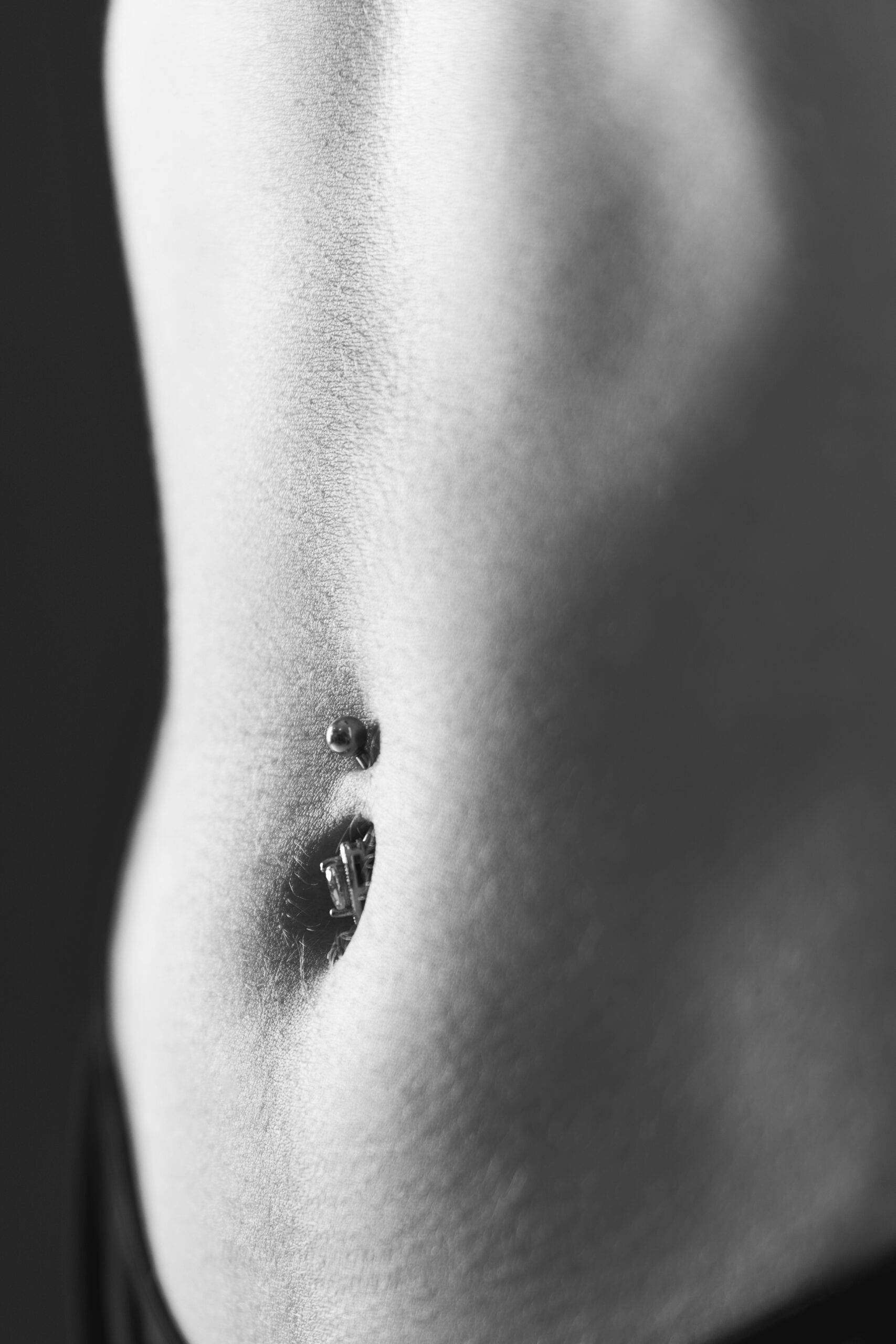 Dettaglio dell’ombelico con piercing in un ritratto femminile in bianco e nero, servizio About Me a Padova