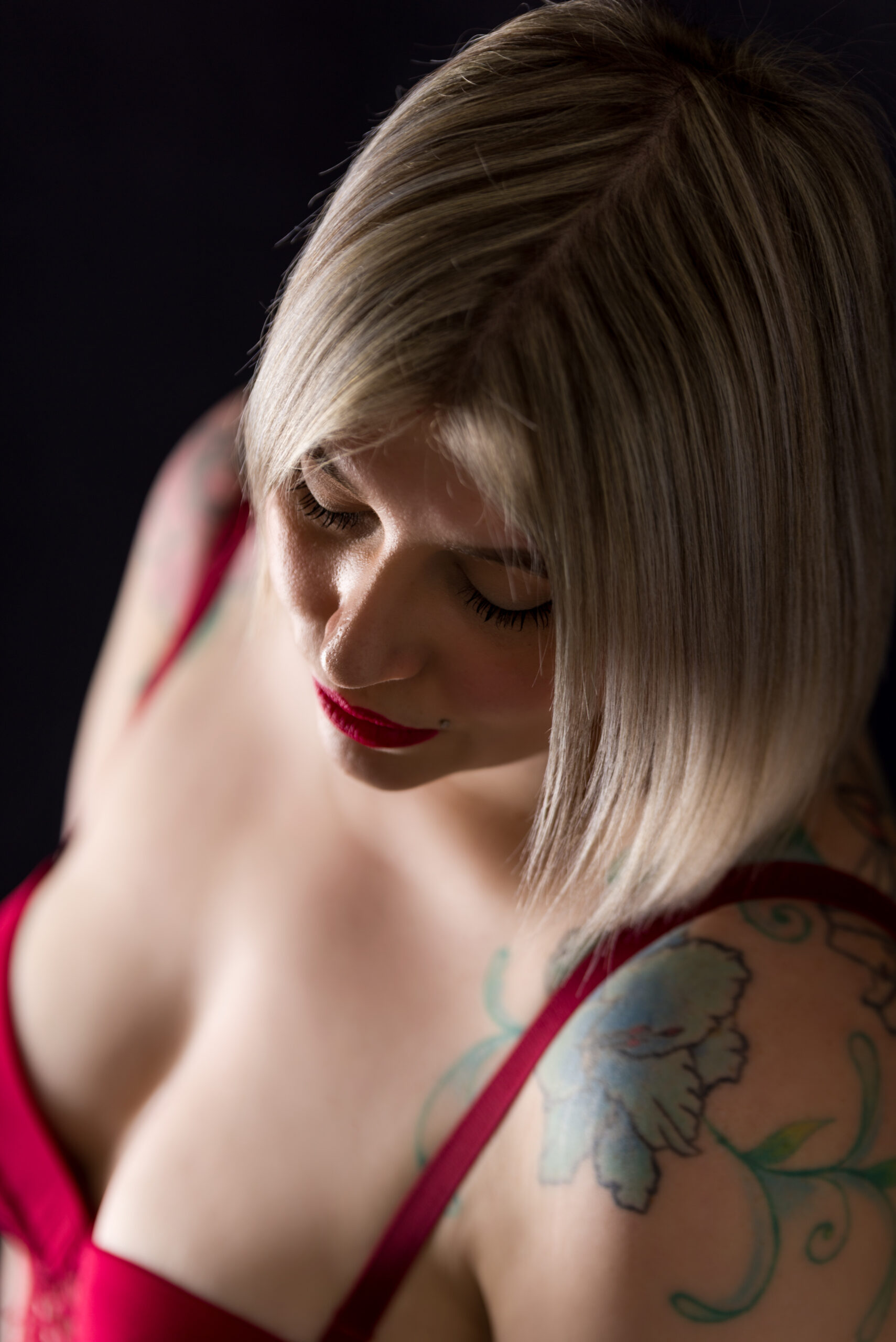 Primo piano di donna con lingerie rossa e tatuaggio floreale sulla spalla, servizio About Me a Padova