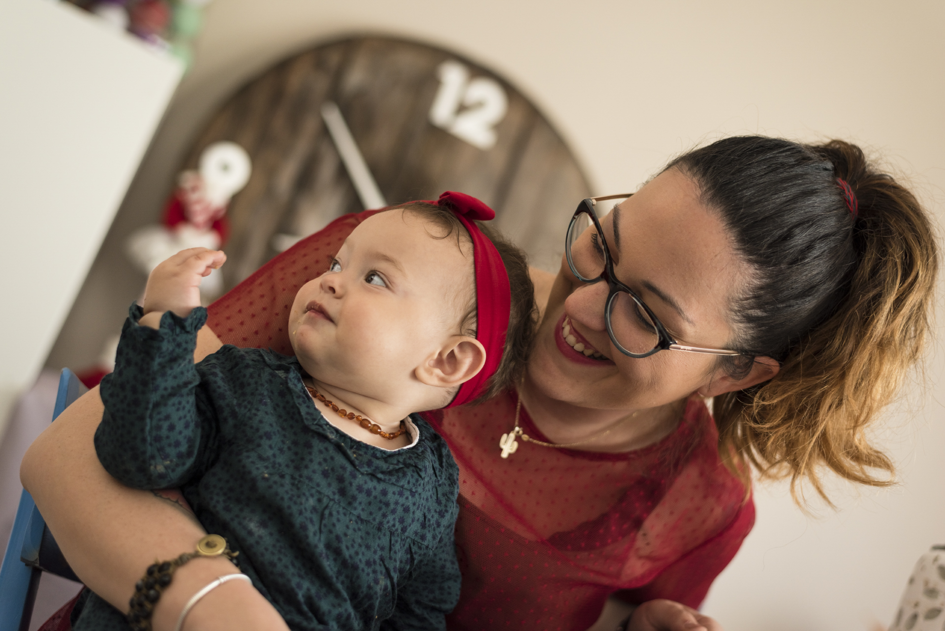 Mamma con occhiali che tiene in braccio una bambina con fiocco rosso, progetto Storie di famiglia a Padova