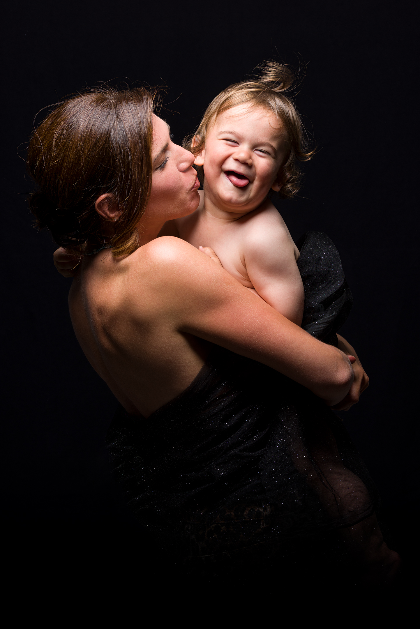Mamma che bacia un bambino sorridente, ritratto in studio del progetto Storie di famiglia a Padova