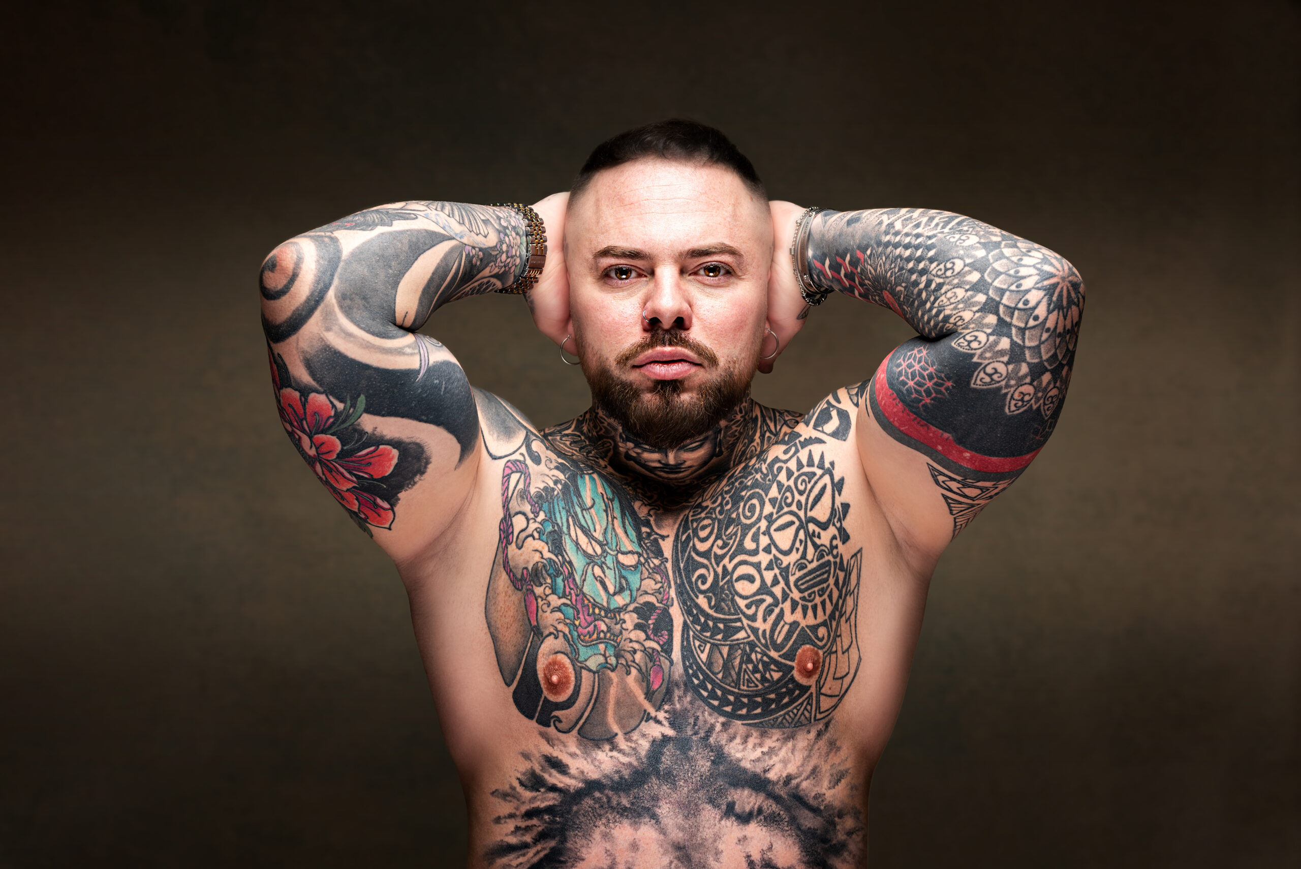 Ritratto in studio di uomo tatuato con le braccia sollevate, progetto Storie di sé a Padova